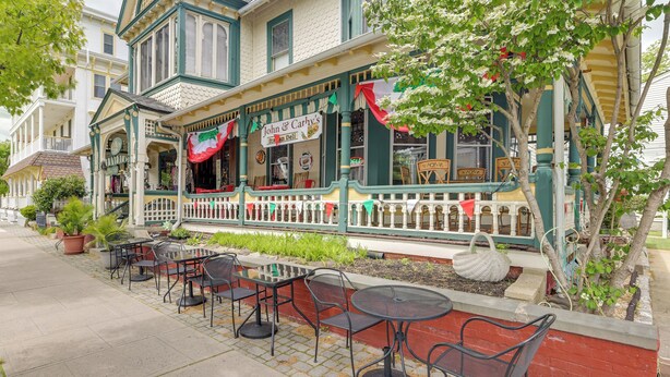 A historic building with a porch, outdoor seating, and a sign for 'John & Carh's Ice Cream Parlour.' - Steps to Beach, Boardwalk & Eats! Ocean Grove Unit (Ocean Grove)