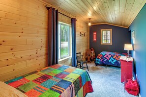 Une cabine avec deux lits, un plafond en bois et une fenêtre.