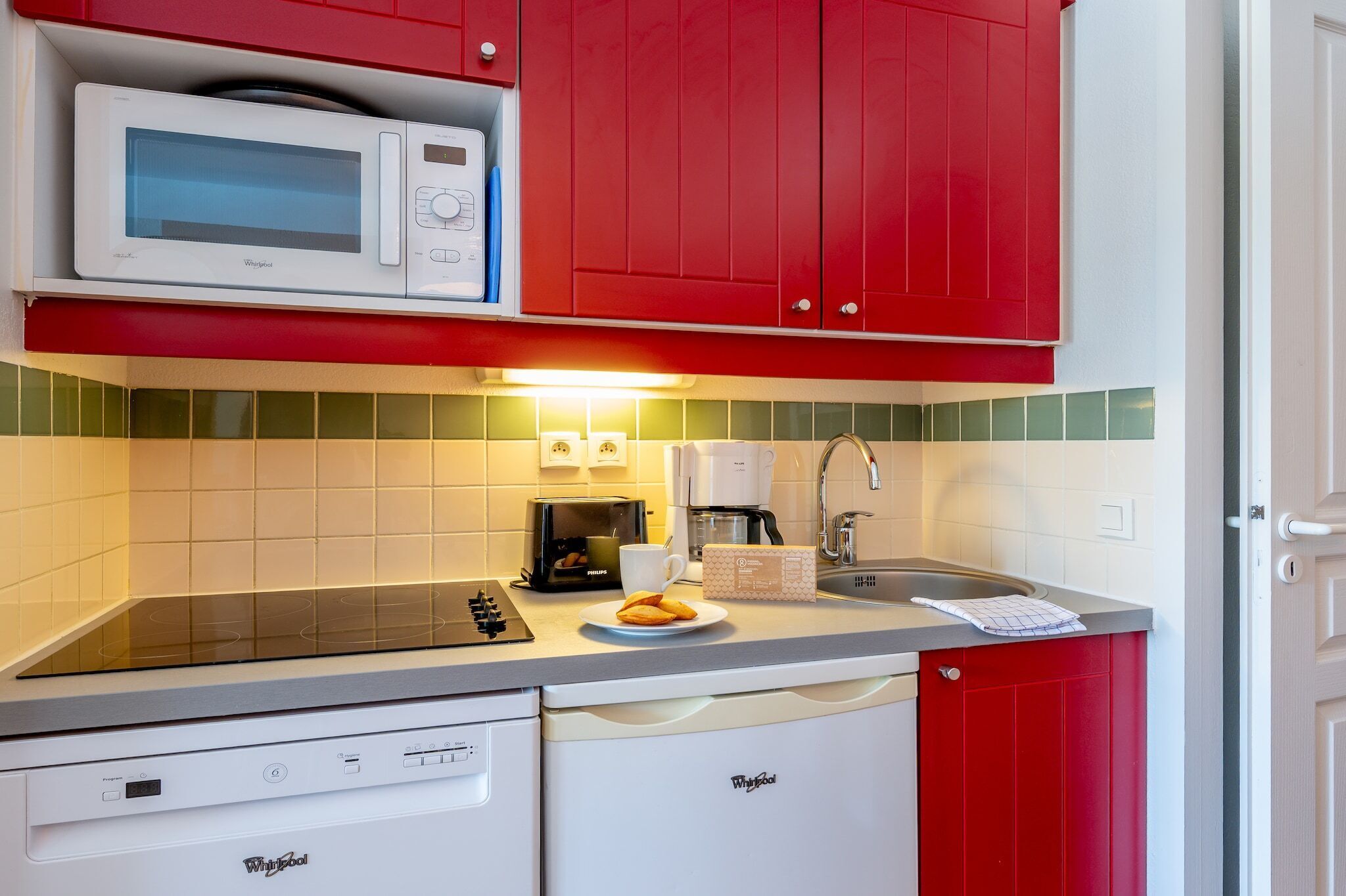 A compact kitchen with a microwave, toaster, coffee maker, and dishwasher.