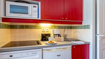 A compact kitchen with a microwave, toaster, coffee maker, and dishwasher.