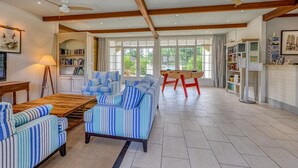 Un vaste espace de vie agrémenté de canapés à rayures, d’une table basse en bois et d’un ventilateur de plafond.