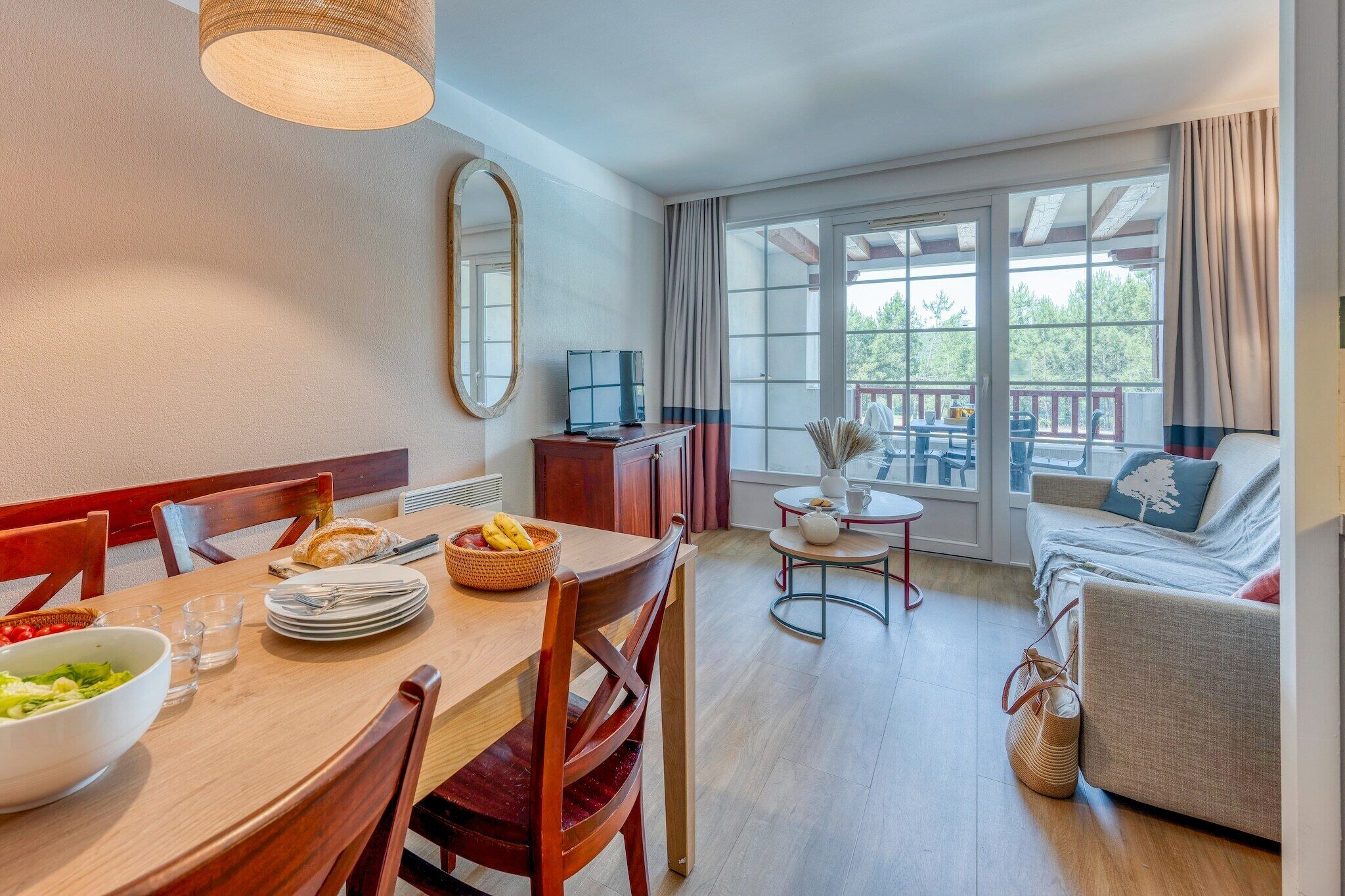 A dining area with a table set for two, a sofa, and a balcony with a view.