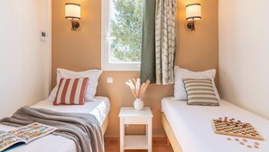 A twin room with two beds, a window, a small table with a vase, and wall-mounted lamps. - Stay with Private Outdoor Space (Mallemort)