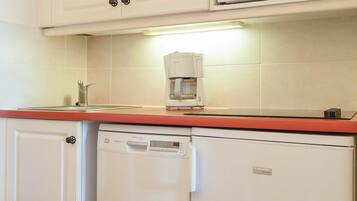 Una cocina equipada con cafetera, lavavajillas y microondas.
