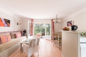 Une pièce confortable avec un canapé, une table à manger, des chaises, un coin cuisine et une grande fenêtre.