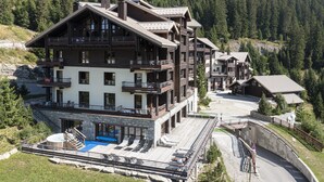 Eine mehrstöckige Lodge mit Balkonen, einem Poolbereich und einer Bergkulisse.