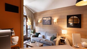 Ein Hotelzimmer mit einer Holzwand, einem Sofa, einem Tisch mit einer Kaffeemaschine und einer Lampe.