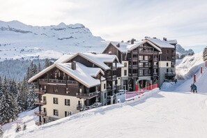 Ein mehrstöckiges Lodge-Gebäude mit Balkonen vor verschneiten Bergen.
