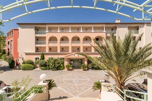 Ein mehrstöckiges Hotel mit Innenhof, Balkonen und Palmen.