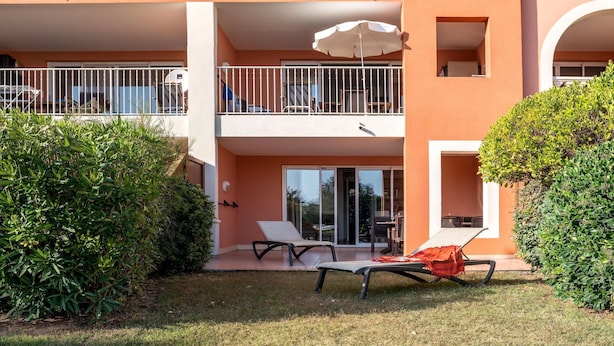 A two-story building with a balcony, a lawn with two lounge chairs, and a large umbrella. - Beautiful French Riviera Apartment for 6 (Les Issambres)