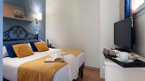 A hotel room with a bed, a television, a tray with a cup and a book, and a wall-mounted shelf with a cactus decoration. - Beautiful French Riviera Apartment for 6 (Les Issambres)