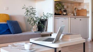 Un salon moderne avec un canapé, une table basse sur laquelle se trouve un ordinateur portable, une bibliothèque et une plante en pot.