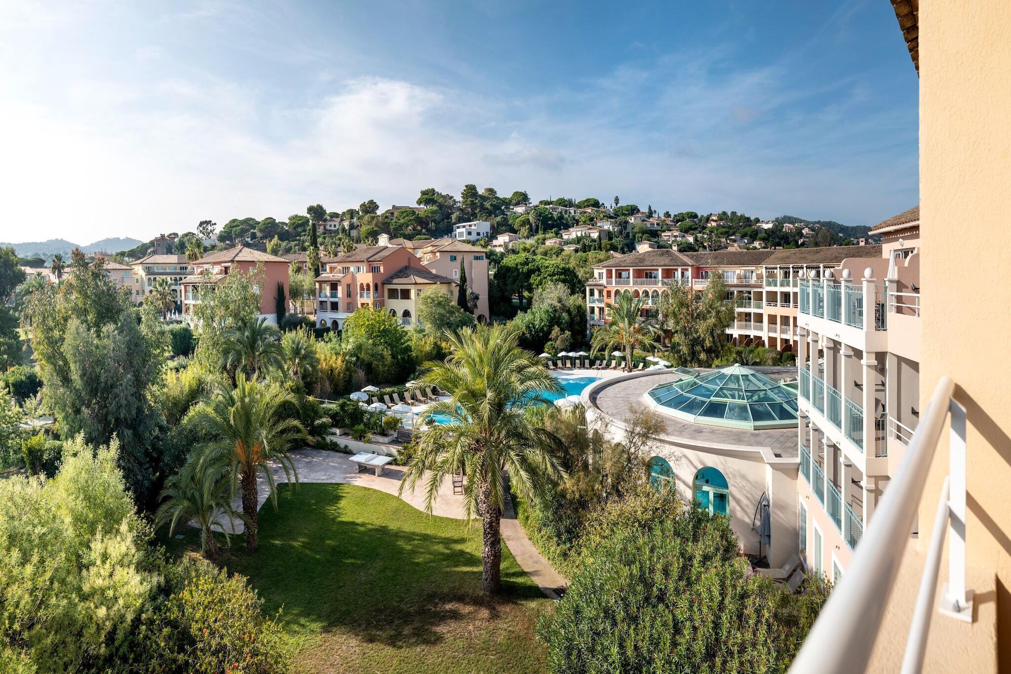 A hotel with multiple buildings, a swimming pool, and lush greenery.