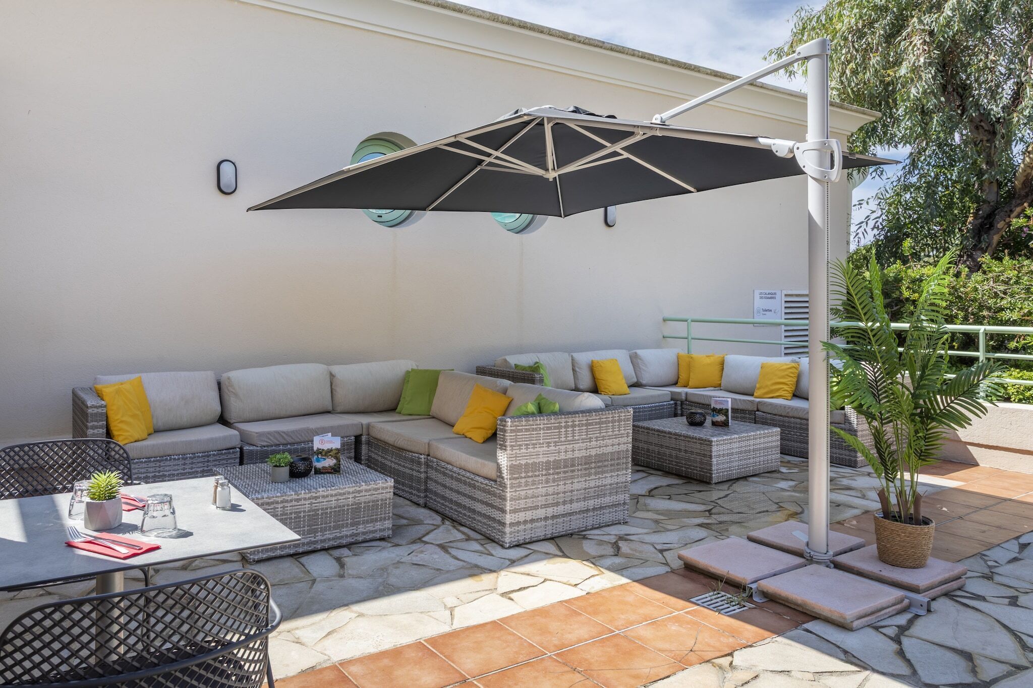 An outdoor seating area with a sectional sofa, a table, and a potted plant.