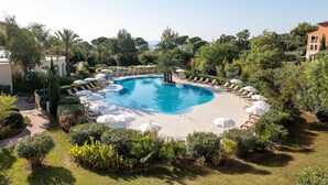 A circular pool with lounge chairs and umbrellas, surrounded by well-maintained greenery and a clear sky. - Stunning 4-Person Sea View Haven (Les Issambres)