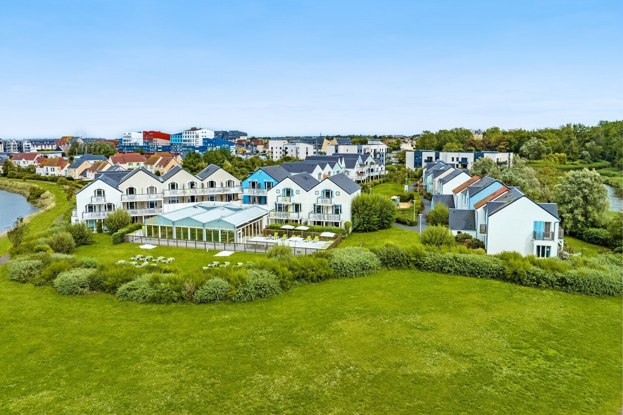 A residential area with modern houses, a river, and a distant cityscape.