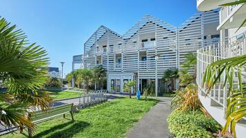 Ein modernes Gebäude mit einer markanten, geometrischen Fassade, einem gepflasterten Weg und einer Bank.