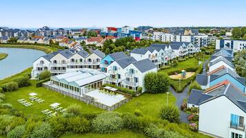 Un quartier résidentiel avec des maisons modernes, un grand bâtiment doté d’un toit en verre et un lac.