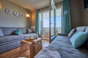 Ein modernes Wohnzimmer mit einer Couch, einem Holztisch und Blick ins Freie.