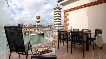 Un balcon avec une table dressée pour le dîner, des chaises et une vue sur la marina, avec ses bateaux et ses bâtiments.