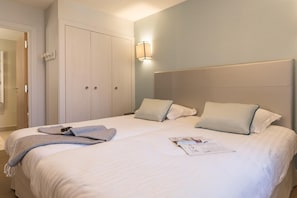 Ein ordentlich bezogenes Bett mit Kissen, einer Nachttischlampe und einer Zeitschrift darauf.