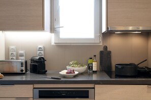 A modern kitchen with a toaster, coffee maker, and a bowl of vegetables. - Premium Deauville Spa Apartment for 8 (Deauville)