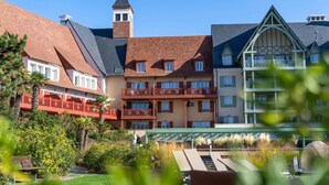 Un hotel con diversi edifici, una torre e un'area giardino con lettini.