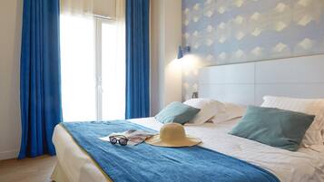 Een hotelkamer met een bed, blauwe gordijnen, een hoed en een tijdschrift.