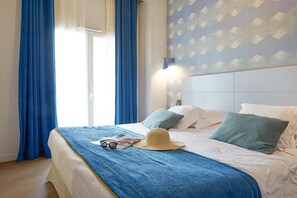 A hotel room with a bed, blue curtains, a hat, and a magazine. - Picturesque Deauville Apartment for 6 (Deauville)