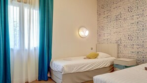 Una camera da letto con un letto, un comodino, tende e una parete decorata.