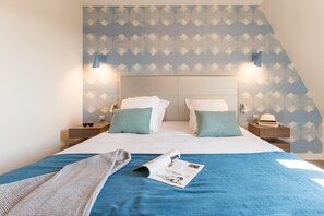 A hotel room with a bed, two bedside tables, a nightstand, a blue blanket, and a magazine on the bed. - Deauville Duplex for 6 with Terrace (Deauville)