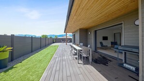 Eine moderne Außenpatio mit Holzterrasse, Essbereich und Bergblick.