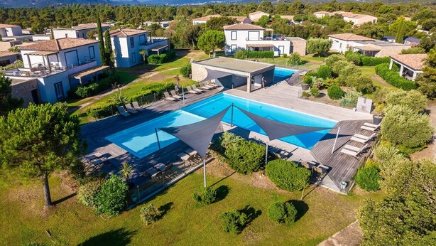 Un quartier résidentiel doté d’une piscine, de maisons et bordé par des montagnes.