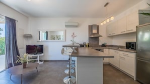 A modern kitchen with a central island, stainless steel appliances, and a flat-screen TV. - Lecci Apartment with Outdoor Pool (Porto-Vecchio)