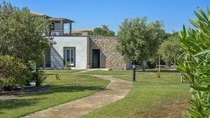 A modern building with a stone facade, a paved pathway, and surrounding greenery. - Corsican Flat with Pergola (Porto-Vecchio)