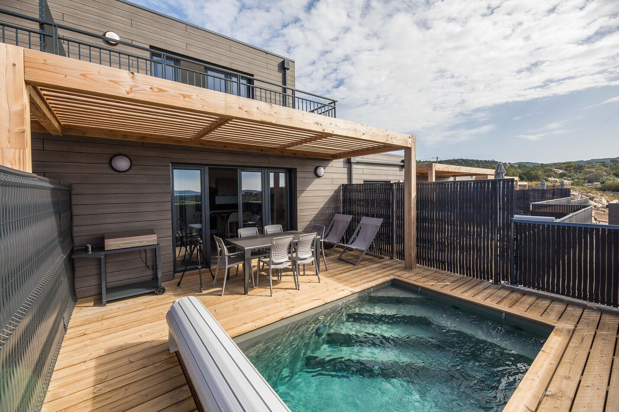 Une terrasse extérieure moderne dotée d’une piscine, d’un espace repas et d’un coin salon abrité.