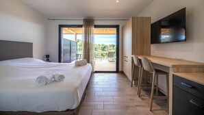 Une chambre d’hôtel moderne équipée d’un lit, d’un bureau, d’une télévision et d’un balcon avec vue.