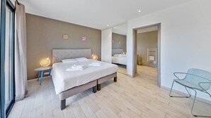 Une chambre d’hôtel moderne avec un grand lit, des tables de chevet, une chaise et un miroir.