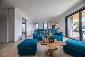 A modern living room with a sofa, ottomans, and a coffee table. - Green Corsican Oasis with Pool (Porto-Vecchio)