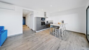 Eine moderne Küche mit Essbereich, Holzboden und einem blauen Sofa.
