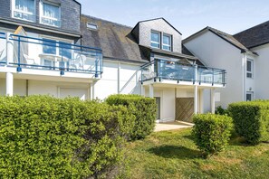 A residential building with a covered outdoor area, a staircase, and a small garden. - Beautiful 8-Person Family Duplex (Île-aux-Moines)