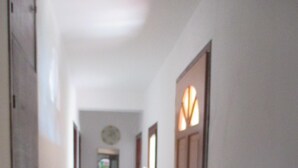 A narrow hallway with doors on both sides, a light fixture on the right, and a small window at the end. - in Cavalaire-sur-Mer by Interhome (Cavalaire)
