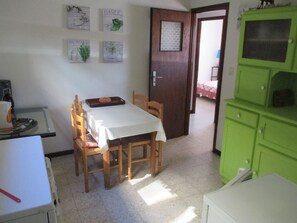 Ein Essbereich mit Tisch, Stühlen und einem grünen Schrank.