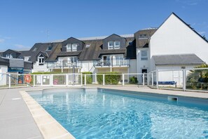 A swimming pool with a white building in the background. - Picturesque 4-Person Coastal Escape (Île-aux-Moines)
