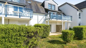 Ein Wohngebäude mit überdachter Terrasse, einer Treppe und einem kleinen Garten.