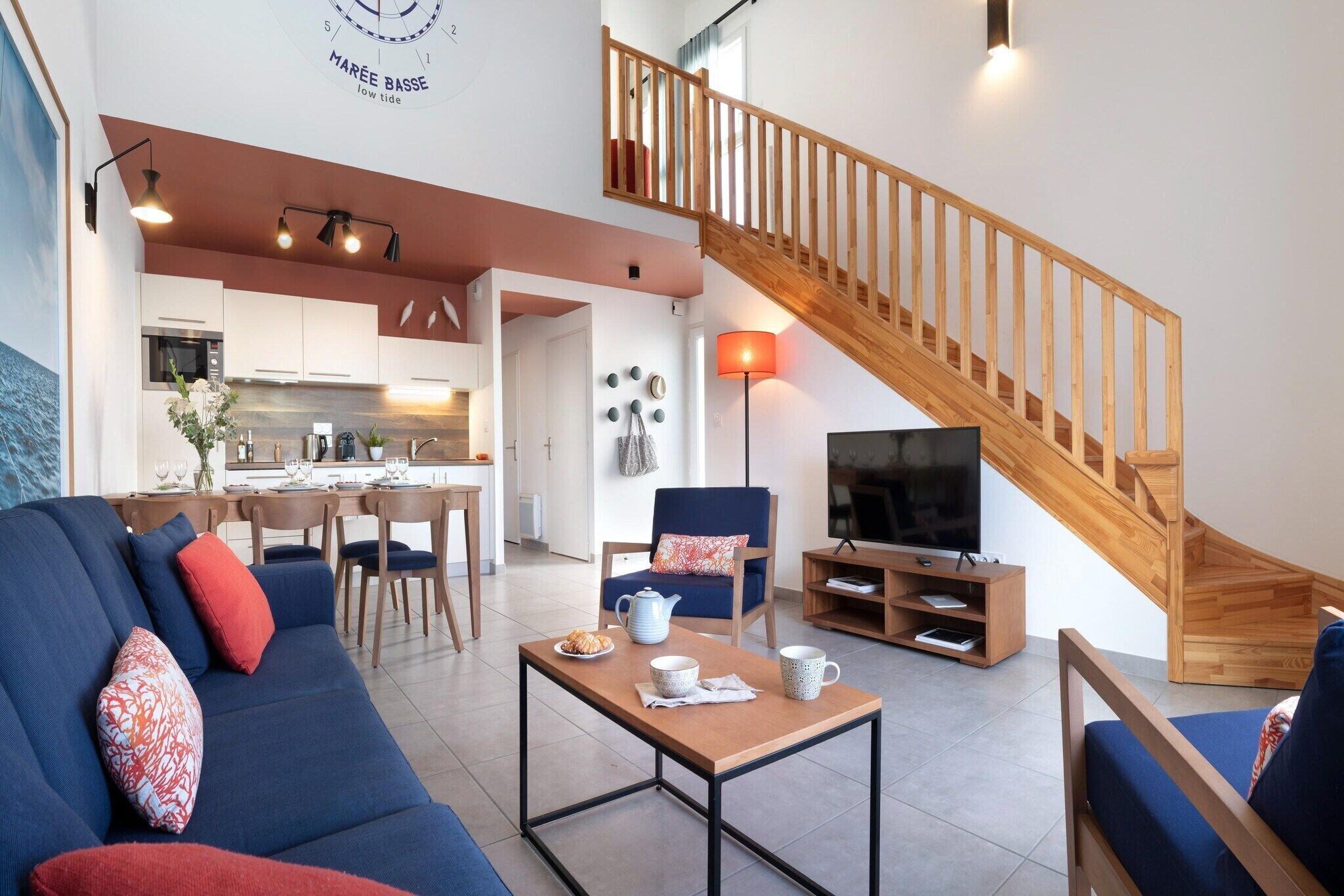 Ein modernes Wohnzimmer mit einer Couch, einem Couchtisch, einem Fernseher und einer Holztreppe.