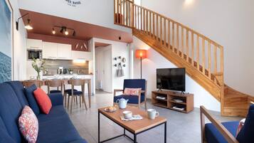 Ein modernes Wohnzimmer mit einer Couch, einem Couchtisch, einem Fernseher und einer Holztreppe.