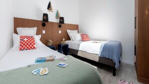 Een hotelkamer met twee bedden, houten hoofdeinden, wandlampen en een kledingkast.