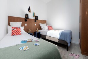 A hotel room with two beds, wooden headboards, wall-mounted lamps, and a wardrobe. - Picturesque 6-Person Duplex Oasis (Les Sables-d'Olonne)