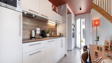 A modern kitchen with white cabinets, a wooden countertop, and a dining area with a table set for two.